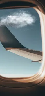 View of an airplane wing through a window with blue sky and clouds.