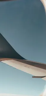 Airplane wing seen from window against a clear blue sky.