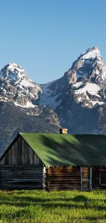 Rustic cabin with snow-capped mountains in the background.