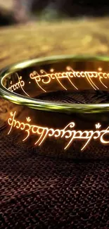 Golden ring with intricate script on textured background.