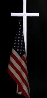 American flag hanging on a white cross with a dark background.