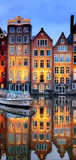 Night view of Amsterdam canal houses with reflections on the water.