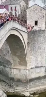 Tourists on ancient stone bridge over scenic river.