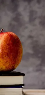 A red apple on books with a grey background.