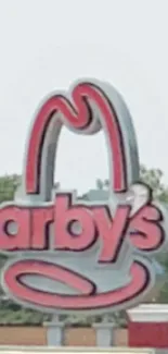 Vibrant red Arby's sign under a clear sky.