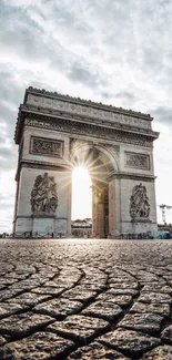 Arc de Triomphe under a glowing morning sky with cobbled streets.