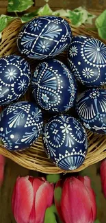 Blue Easter eggs with floral designs in a basket, surrounded by tulips.