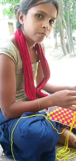 Young girl crafting with colorful yarn outdoors.