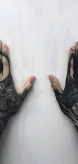 Detailed black hand tattoos on both hands against a light gray background.