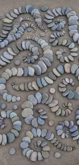 A circle of artfully arranged pebbles on a grey sandy surface, ideal for phone wallpaper.