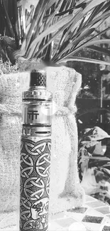 Black and white image of a decorative vape mod with intricate patterns.