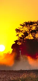 Silhouetted ATV riders at sunset with vibrant orange hues.