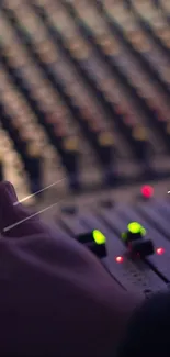 Hand on audio mixing console with vibrant lights.