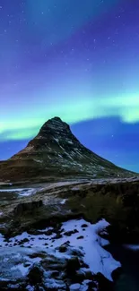 Northern Lights over a snowy mountain with starry night sky.