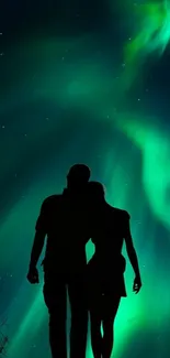 Silhouette of a couple under green aurora borealis.