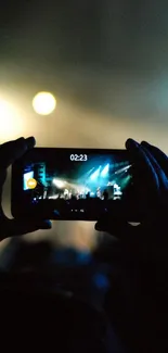 Person capturing concert with smartphone in hand.