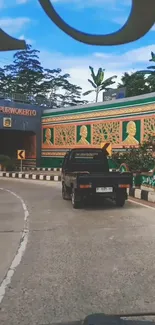 Urban road with vibrant mural and greenery.