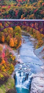 Vibrant autumn landscape with bridge and waterfall.