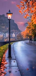 Autumn street with orange leaves and a historic city backdrop at evening.