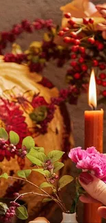 Hand arranging flowers with a candle against autumn backdrop.