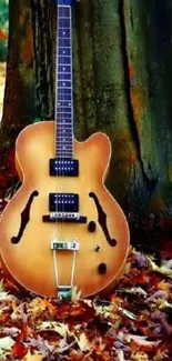 Guitar leaning against tree with autumn leaves.