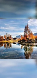 Serene lake reflecting autumn trees and mountains under a blue sky.