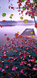 Autumn leaves on wooden pier by a serene lake with misty light.