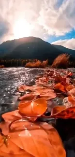 Autumn leaves by a serene lake with mountains and bright sky.