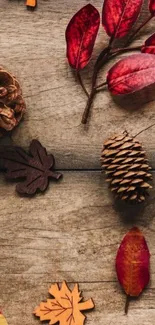 Autumn leaves and pinecones on wood background wallpaper.