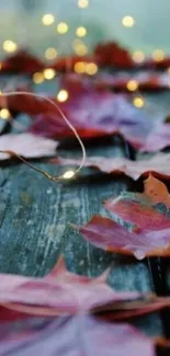 Red autumn leaves with fairy lights on wood.