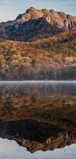 Mountain and autumn foliage reflected in calm lake.