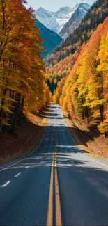 Autumn road winding through colorful forest with mountains in background.