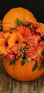 Vibrant orange flowers in a pumpkin vase on wood.