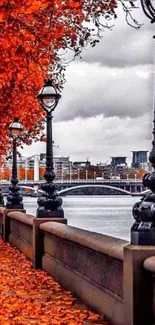 Autumn leaves line a riverside walkway with street lamps.