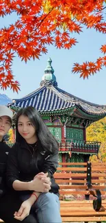 Couple in front of Asian pavilion with colorful autumn leaves.