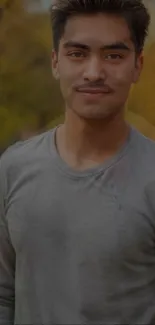 Man in gray shirt with golden brown autumn background.