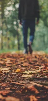 Blurred figure walking on leafy autumn path in forest.