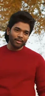 Person in red sweater with fall leaves background.