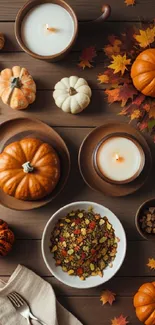 Elegant autumn scene with pumpkins, leaves, and candles on a wooden table.