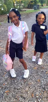 Two young girls in school uniforms, smiling outdoors.