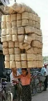 Person balancing large stack of baskets on street.