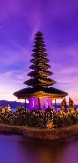 Balinese temple with a purple sky and tranquil waters at night.