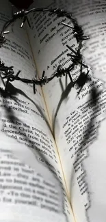 Barbed wire heart casts shadow on an open Bible, creating a unique wallpaper.