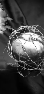 Black and white heart with barbed wire on moody background.