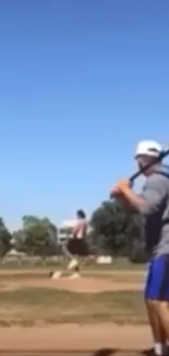 Baseball player about to swing under a clear blue sky.