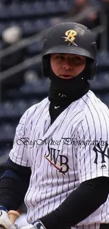 Baseball player in uniform with helmet, standing at bat in stadium.