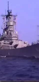 Battleship sailing in the deep blue sea under a clear sky.