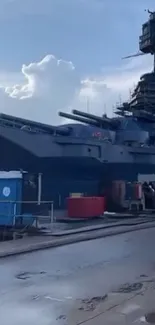 Battleship docked at a harbor on a cloudy day.