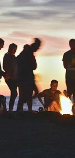 Beach bonfire with silhouettes at sunset.