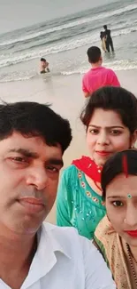 Family taking a selfie at the beach with ocean waves in background.